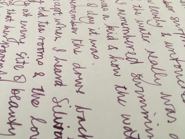 a sideways photo of handwriting in purple ink, close up